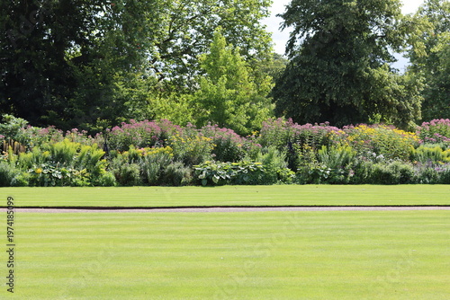 фотографія View across a neatly mown lawn to a large flower bed