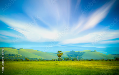 Green mountains contrast with the blue sky and a light mist.