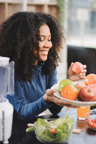Young nutritionist showing bell peppers during an online video call consulting about healthy eating, sitting at home at a table with vegetables, laptop and measuring tape