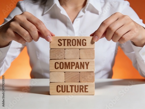 Woman stacking blocks spelling 'strong company culture' with business teamwork employees strategy