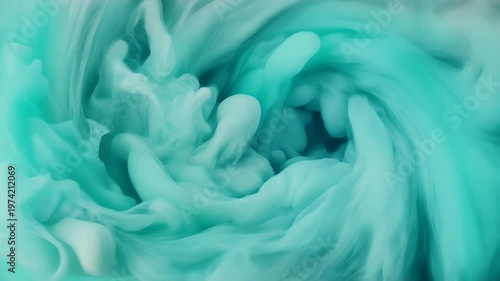 Abstract turquoise ink swirling and blooming in water.