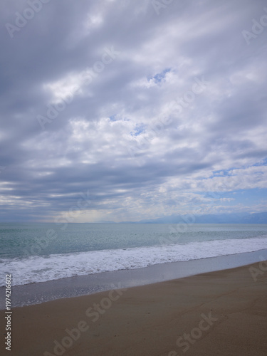 beautiful sandy shore with calm blue water on a cloudy day