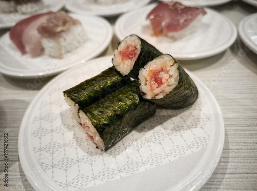 Fresh tuna maki sushi rolls wrapped in crispy nori seaweed, served on a white patterned ceramic plate in a Japanese restaurant