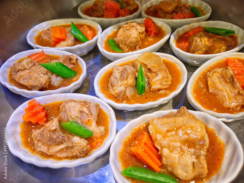 Multiple small white bowls of tender braised pork rib stew garnished with carrots and green beans, served as appetizer portions