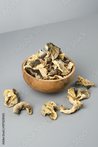 Wooden bowl showcases crispy salmon skin chips on gray surface. Perfect for food blogs, menus, snack packaging, culinary websites.