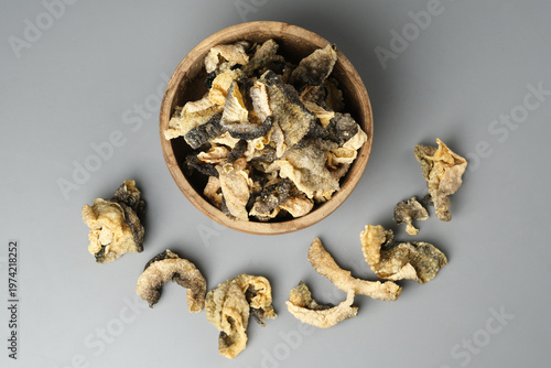 Wooden bowl showcases crispy salmon skin chips on gray surface. Perfect for food blogs, menus, snack packaging, culinary websites.