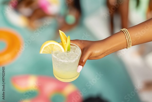 Refreshing Summer Cocktail Held by Woman at Luxury Swimming Pool Resort, Tropical Vacation Drink with Citrus Garnish