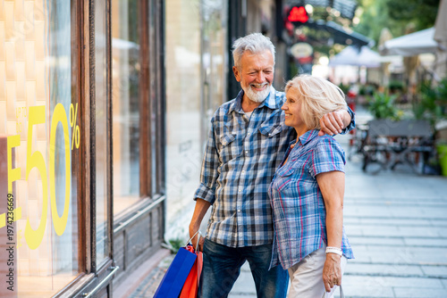 Happy senior couple in front of a shopping window