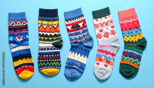 Five colorful patterned socks laid out on a light blue background. Each has a different design and color scheme
