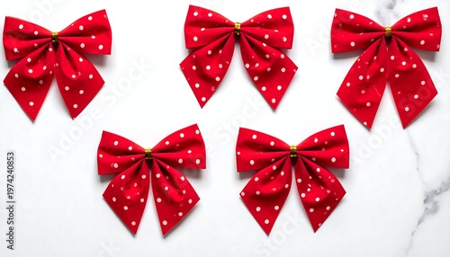 Five decorative fabric bows. Each is red with white polka dots, and has a gold center, arranged on a marble surface