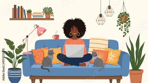 Happy woman working on her laptop while sitting on a comfortable blue sofa at home with two pet cats and indoor plants.