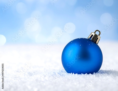 A vibrant blue ornament rests in fluffy snow, against a soft, blurred, light blue backdrop. A close up shot captures the serene holiday scene