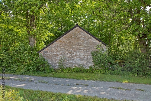 Gable end of an old stone building with trees surrounding it in summer, Koguva village, Muhu, Estonia, Europe.