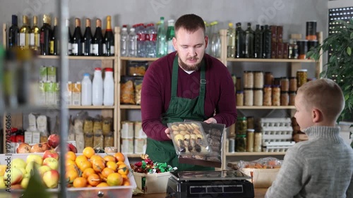 Friendly salesman kindly assisting little boy purchasing cookies in grocery store 