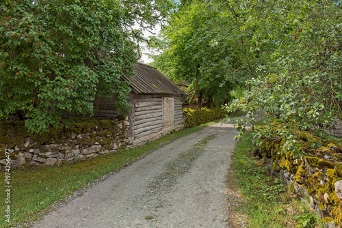 Moss-coverd stone walls along narrow gravel path in summer, Koguva village, Muhu, Estonia, Europe.