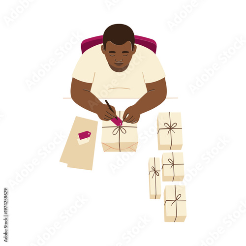 A man sitting at a desk wrapping gifts and writing a letter indoors.