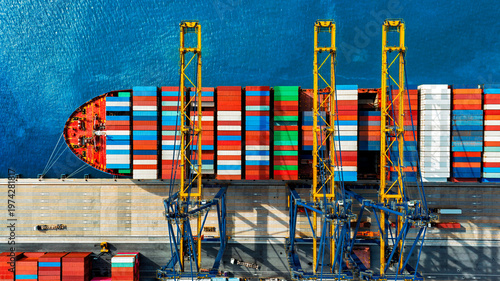 Aerial top view logistics and transportation of container cargo ship and cargo working crane bridge in shipyard.