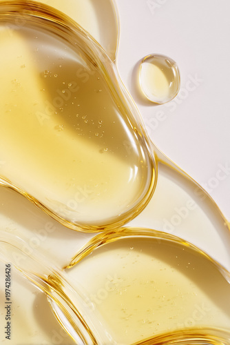 Golden cosmetic gel texture spreading on surface with oil drops illustrating beauty, skincare, and health concepts