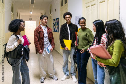 Group of diverse high school or college students standing in a modern school hallway, communicating and socializing between classes