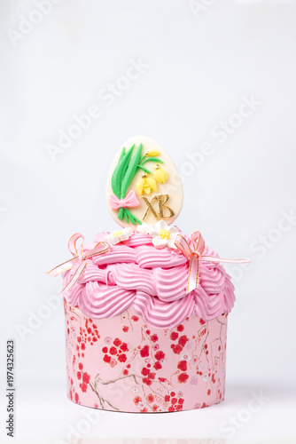 Close-up of pink floral cupcake with Easter egg and XB initials on white