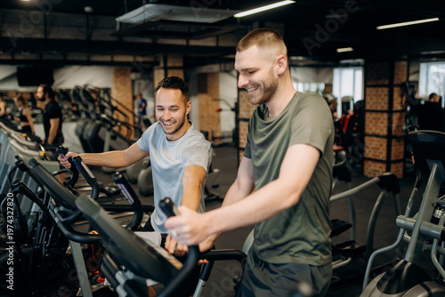 Принти на полотні Two men are exercising at a gym, engaged in cardio workouts on machines