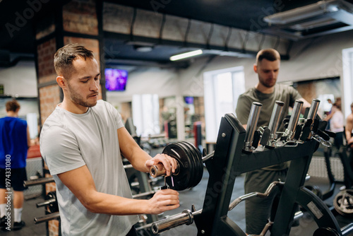 Foto Two men are lifting weights inside a gym