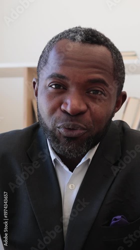 Close-up of an African American man in a suit and tie speaking, with a purple pocket square visible