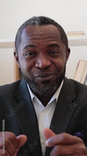 An African American man in a suit and tie gestures with his hands while speaking, conveying enthusiasm and engagement