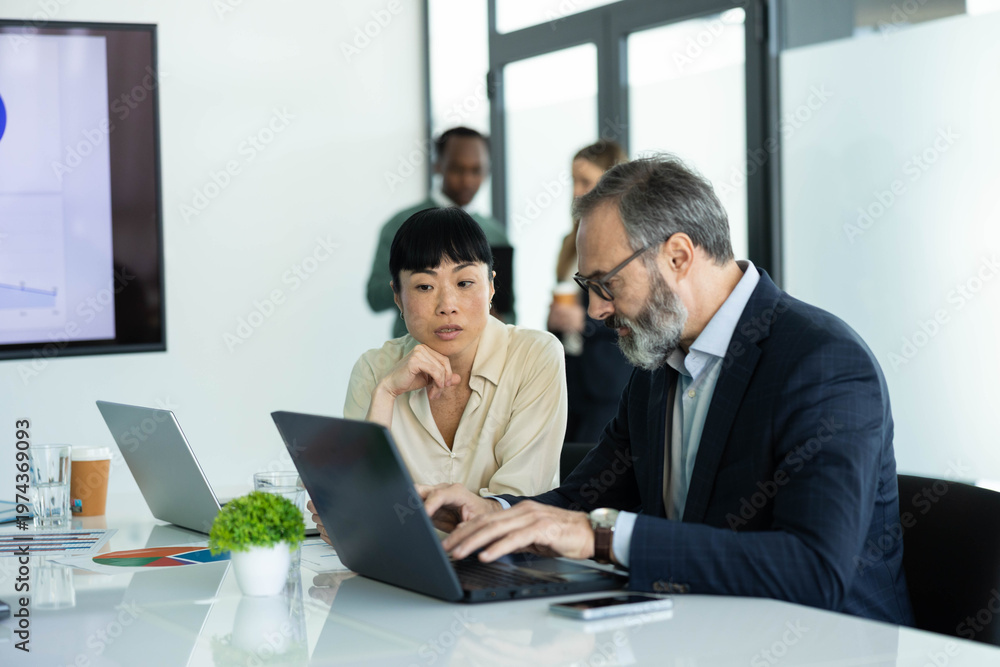 Obraz premium Diverse professionals working together in a modern office, planning strategies and discussing project data during a corporate meeting
