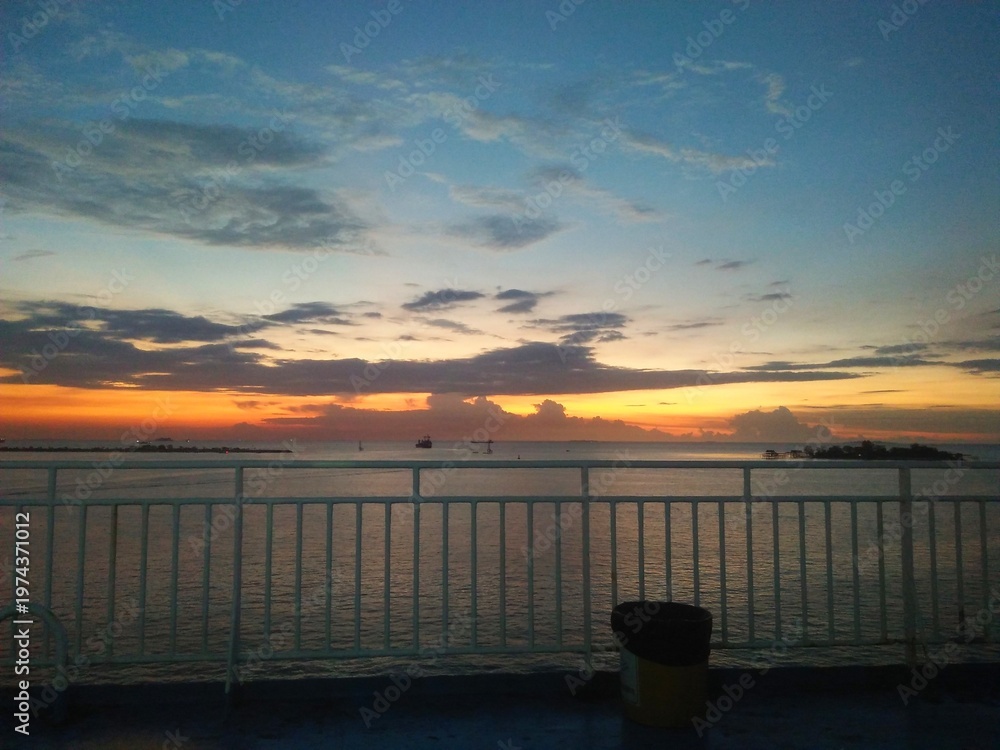 Fototapeta premium Dramatic Sunset View from Fery Ship Deck with Ocean Horizon