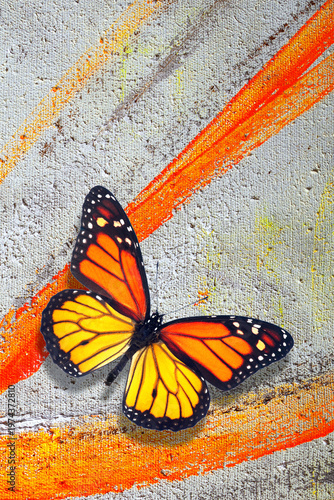 A colorful monarch butterfly on an artist's canvas, painted with brushstrokes of oil paint. Orange color in nature and art. top view