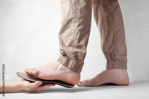 Side view of hand fitting orthopedic insole to foot for correction
