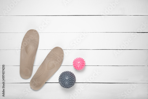 Top view of orthopedic insoles with two massage balls on white floor with copy space