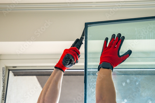 Worker separating triple glazed window glass unit into individual panels for safe handling and disposal after damage in apartment. Window repair, glass recycling and maintenance process concept.