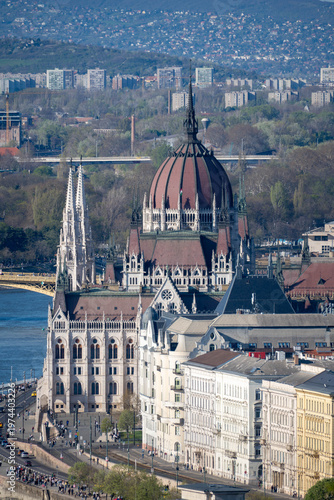 View of the Hungarian Parliament and the Danube in Budapest, with a bridge, boats and layered cityscape under clear spring light.