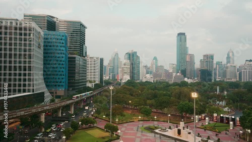 Aerial view of Lumphini Park and the modern Bangkok city skyline with a BTS skytrain passing by, Thailand