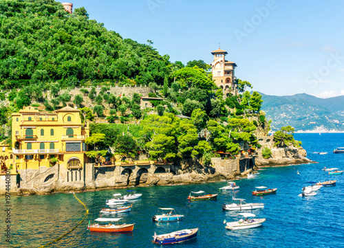 Beautiful italian coastline with green mountains and blue azure sea bay of Portofino gulf in Liguria. Panoramic landscape of luxury italian resort with boats in sea and cloudy sky.