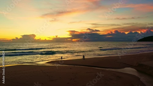  A breathtaking view of the ocean at sunset, showcasing radiant golden and violet hues spreading across the sky and reflecting gently on the calm waves. The serene evokes peace and natural beauty.