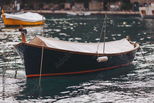 Bild auf Leinwand A small wooden boat gently floats on calm waters, reflecting the surrounding scenery