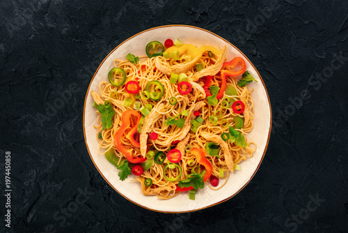 Chow Mein noodles with chicken and vegetables, overhead flat lay shot on black