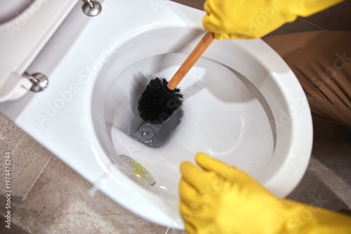 Person cleaning home toilet bowl with chemicals.