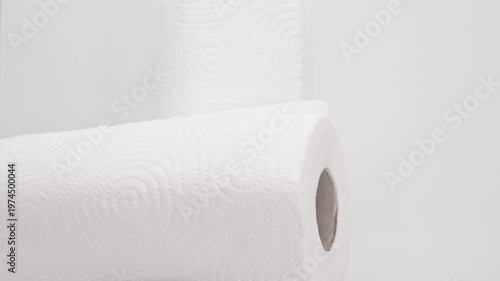 Paper rolls are stacked and arranged on a simple surface in a bright light setting to show different angles and details of the rolls