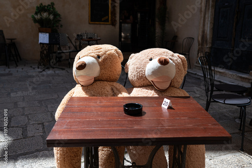 Two teddy bears sitting at a table in a restaurant. Concept of inviting customers to a restaurant. 
