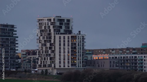 Modern residential apartment buildings in a city district at dusk. Contemporary urban architecture with glowing windows at twilight. Real estate and metropolitan lifestyle concept.
