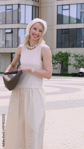 Beautiful young blonde woman model smiling outdoors in urban location. Fashionable female wearing beige summer outfit and accessories, light look, modern city lifestyle, elegance, confidence