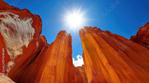 Dramatic orange rock formations under a bright sun in a vibrant blue sky showcasing natural erosion and geological wonders.