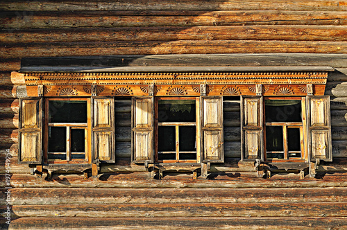 Three windows of the wooden traditional Slavic house built in Slavic country style - rural construction background