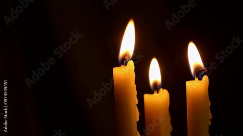 Three flickering candles in a dark setting. Creating a warm and inviting atmosphere for relaxation and meditation