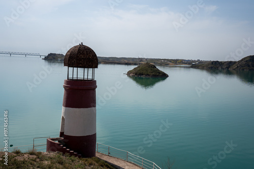 Solitary lighthouse on a pier surrounded by turquoise water. Qonayev, Central Asia