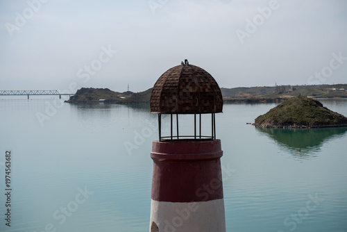 Solitary lighthouse on a pier surrounded by turquoise water. Qonayev, Central Asia